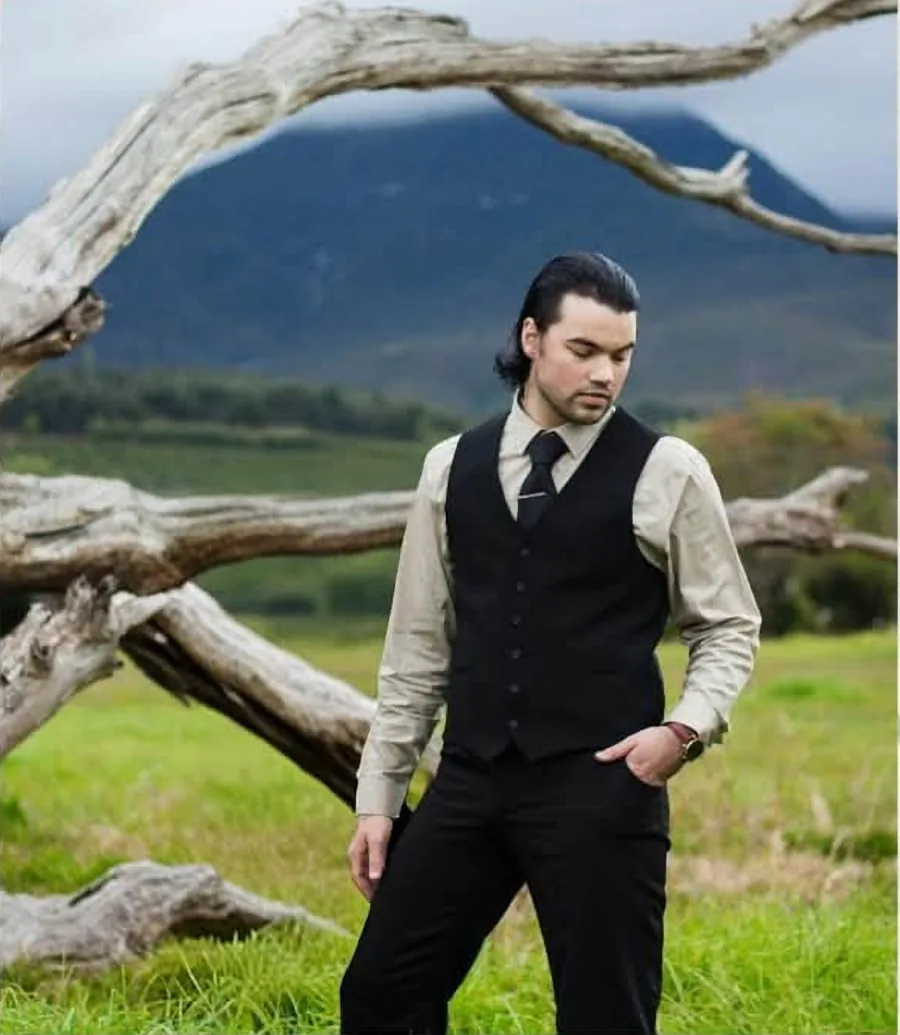 Flippie Blaauw, founder of Filipé, standing in a green field with mountains behind him